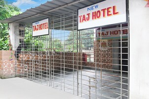 Entrada de un hotel con una reja metálica y un letrero que dice 'NEW TAJ HOTEL'.