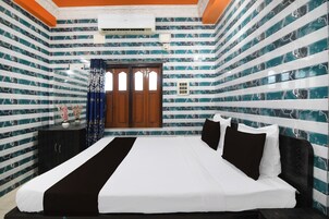 Un dormitorio con una cama grande, una ventana con cortinas y una pared con diseño a rayas.