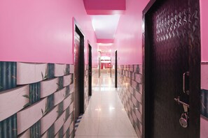 Un pasillo con paredes rosadas y piso estampado que conduce a una habitación con una puerta.