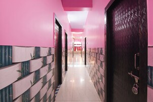 Un pasillo con paredes rosadas y piso estampado que conduce a una habitación con una puerta.