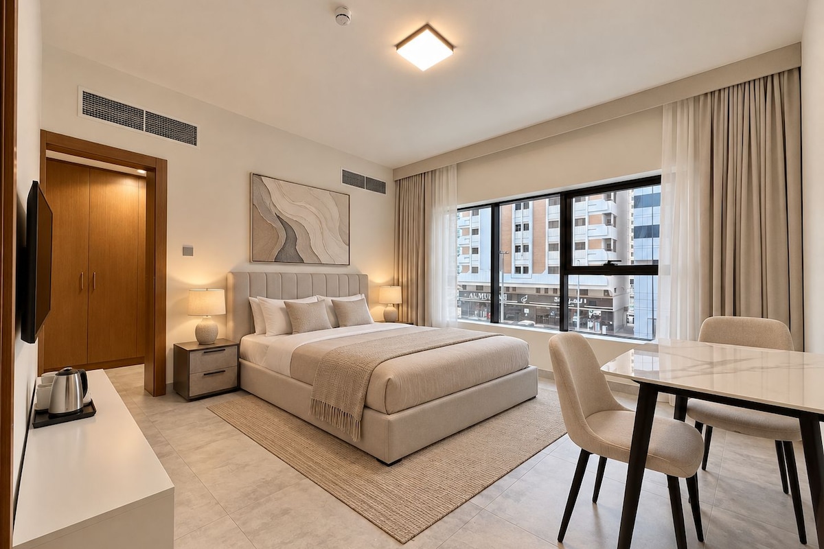A modern hotel room with a bed, bedside tables, a desk, and a chair.