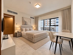 Una habitación de hotel moderna con una cama, mesitas de noche, un escritorio y una silla.