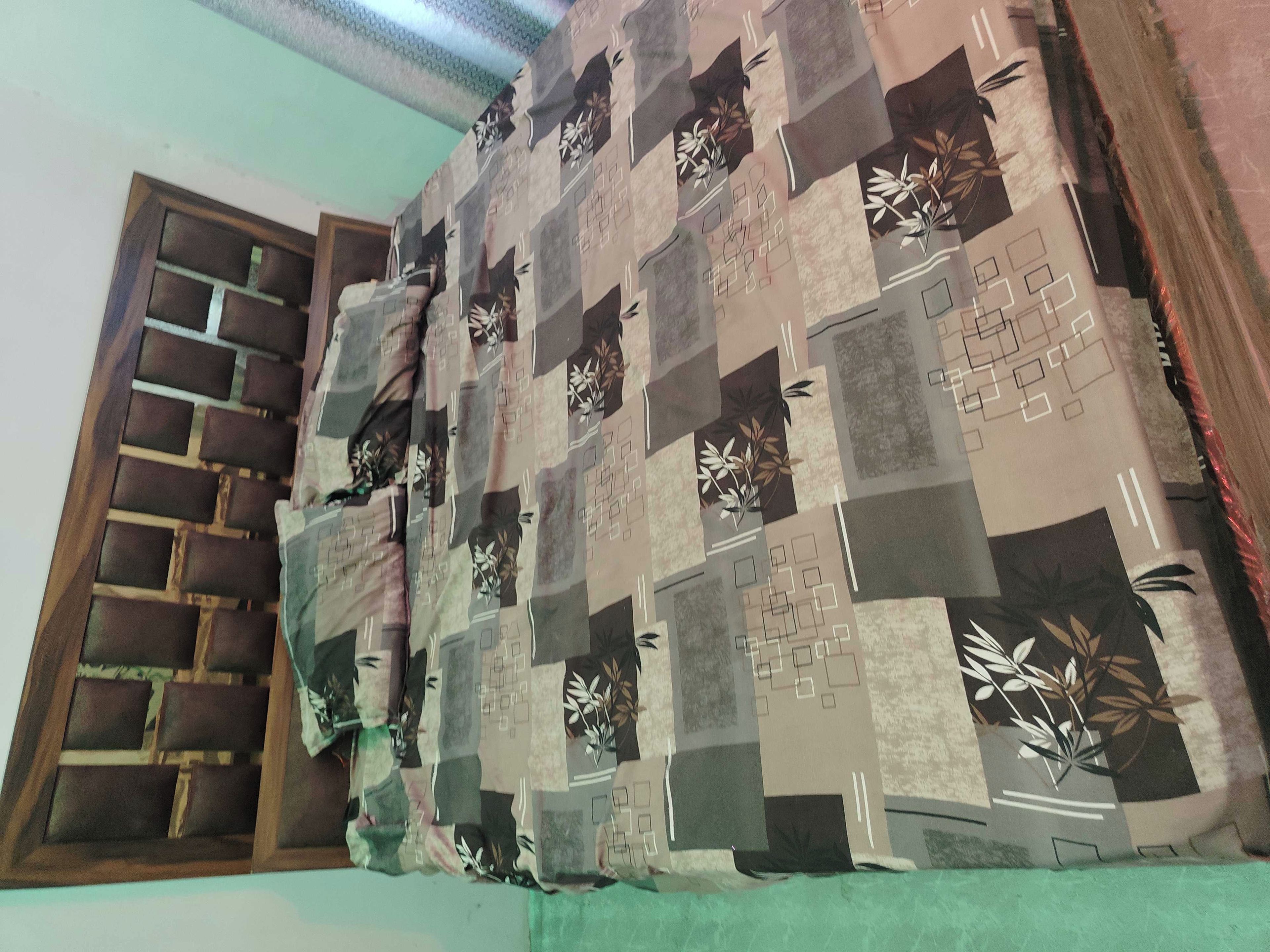 Una habitación con una cortina estampada, una ventana con diseño de cuadrícula y una pared con motivo geométrico.