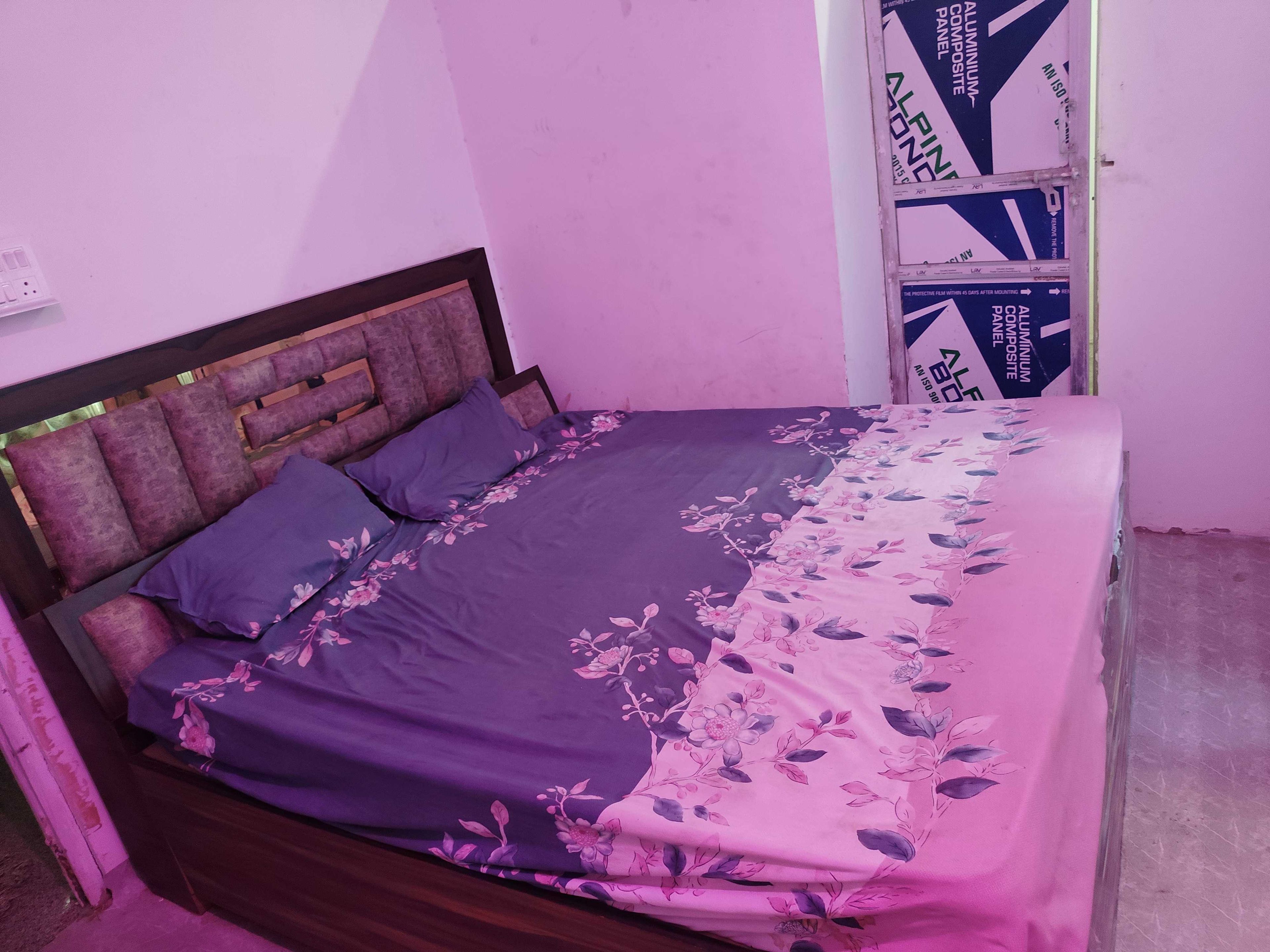 A bed with a floral bedspread and a headboard with a geometric design.