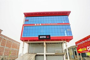 A hotel building with a red and blue facade, a sign reading 'OYO THE KING HEAVEN', and a signboard with hotel name in Hindi. - Hotel O THE KING HEAVEN (Bhongaon)