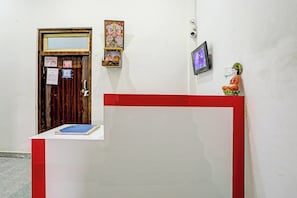 A reception area with a wooden door, a small shrine, a framed picture, and a television mounted on the wall. - Hotel O THE KING HEAVEN (Bhongaon)