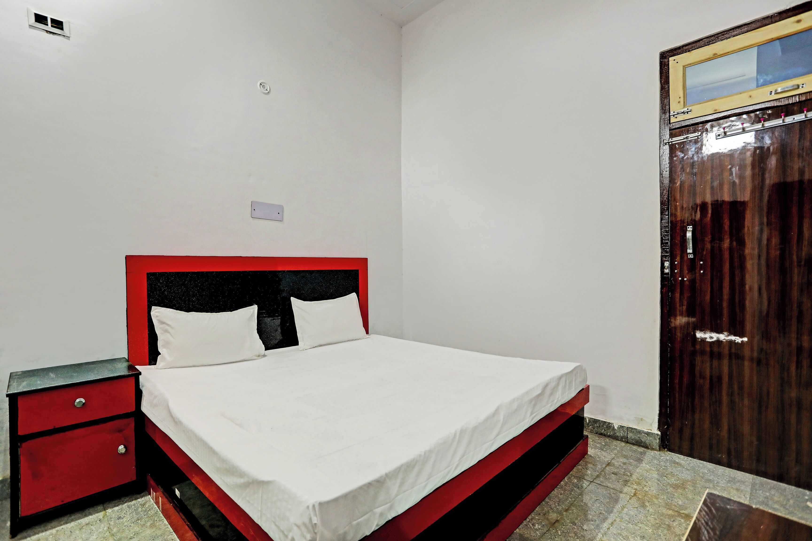 A bedroom with a single bed, a nightstand, a wardrobe, and a mirror.