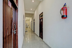A hallway with wooden doors, a fire extinguisher mounted on the wall, and a sign indicating room number 107. - Hotel O THE KING HEAVEN (Bhongaon)