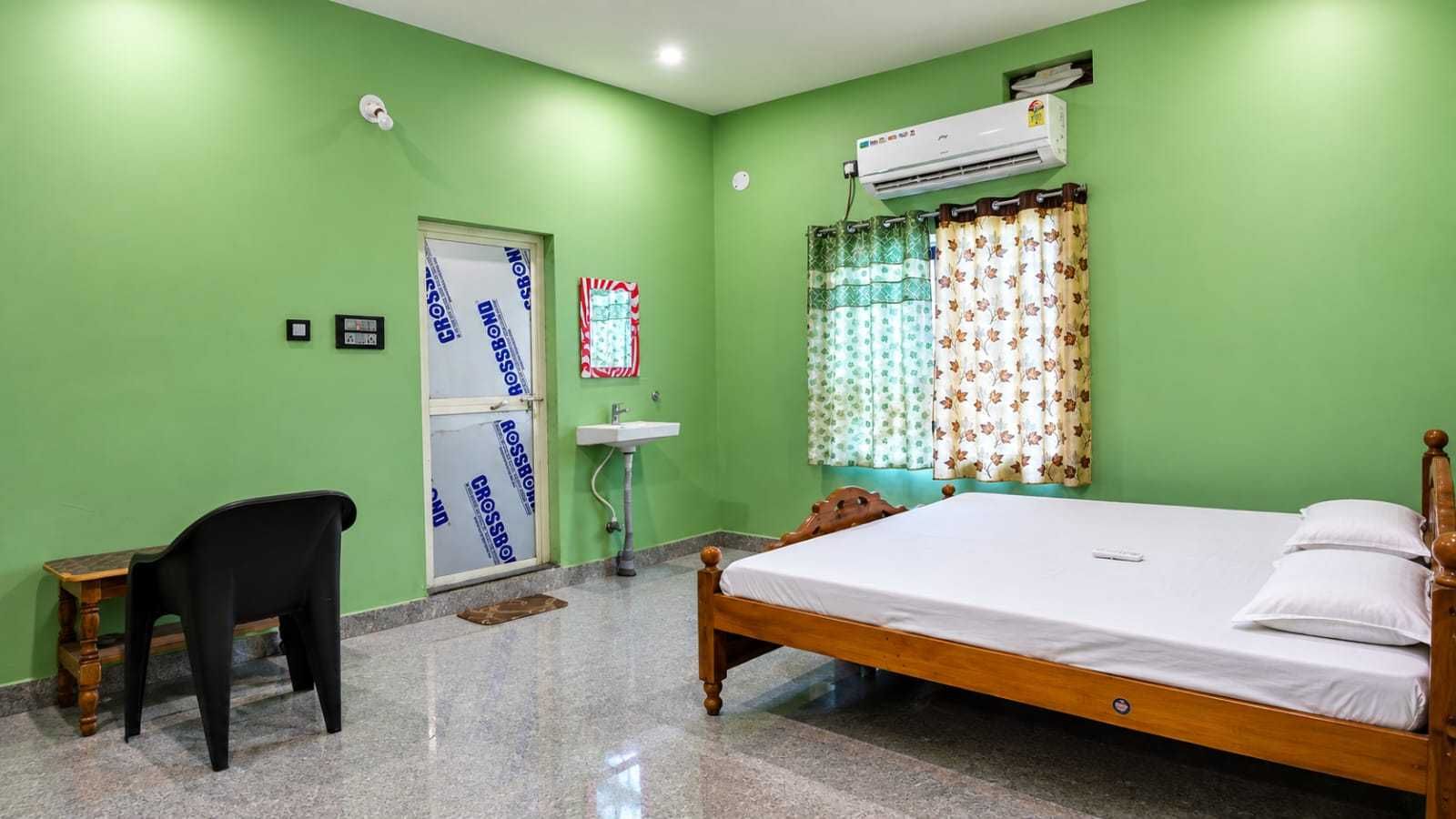 A room with a bed, a chair, a sink, and an air conditioning unit.