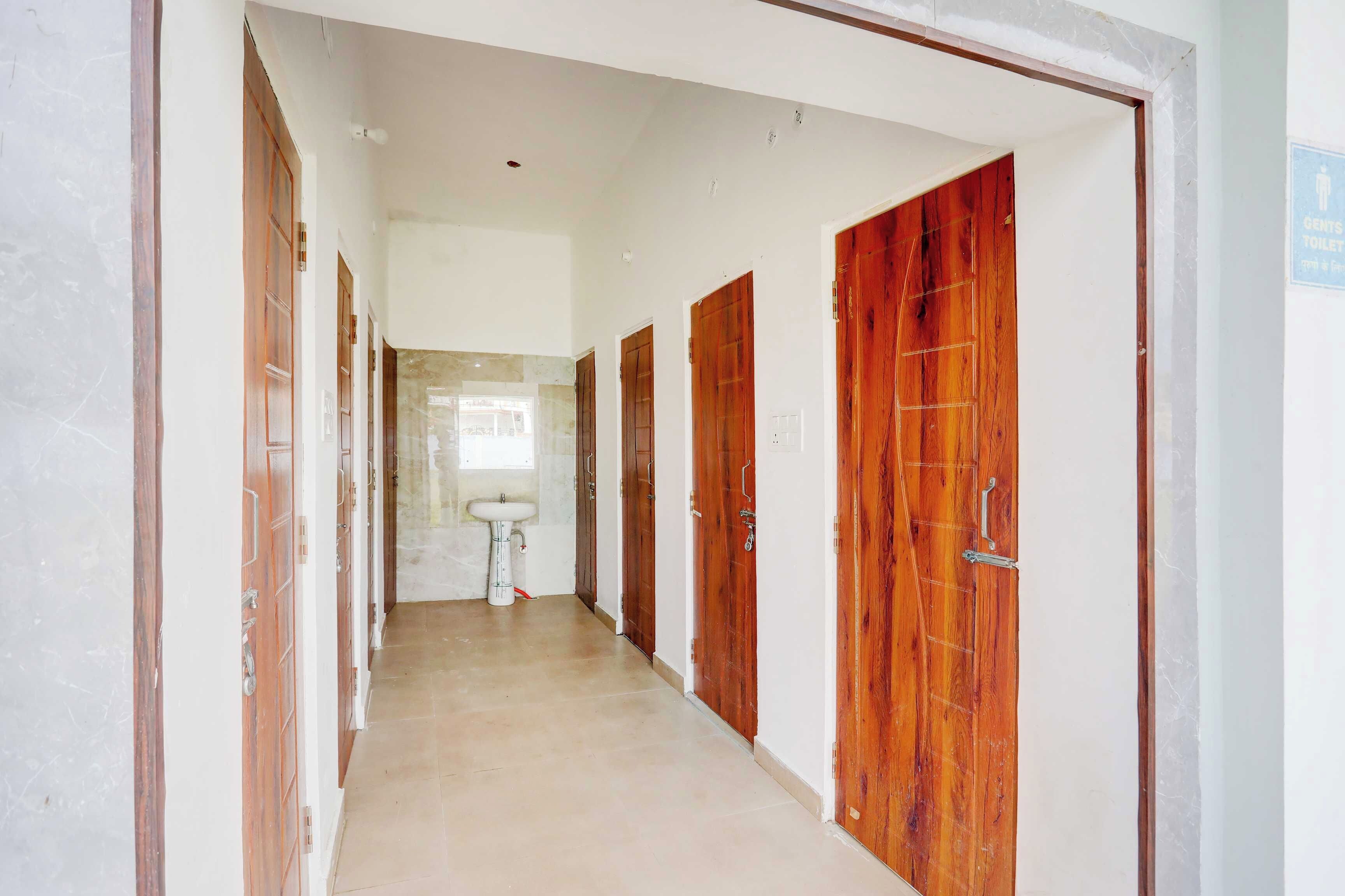 Un couloir avec des portes en bois, un sol carrelé et un lavabo blanc.