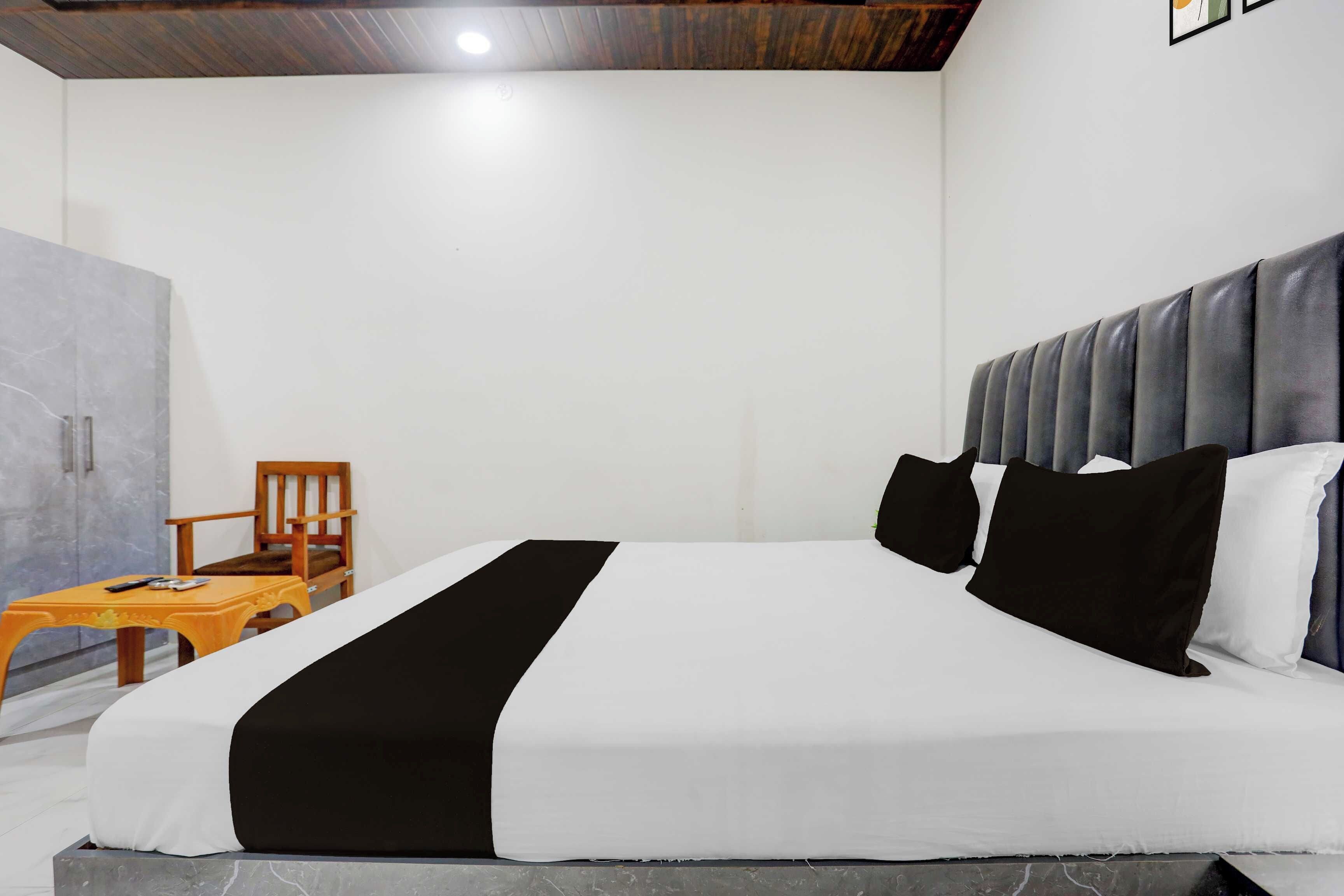 A hotel room with a bed, a wooden chair, a small table, and a wardrobe.
