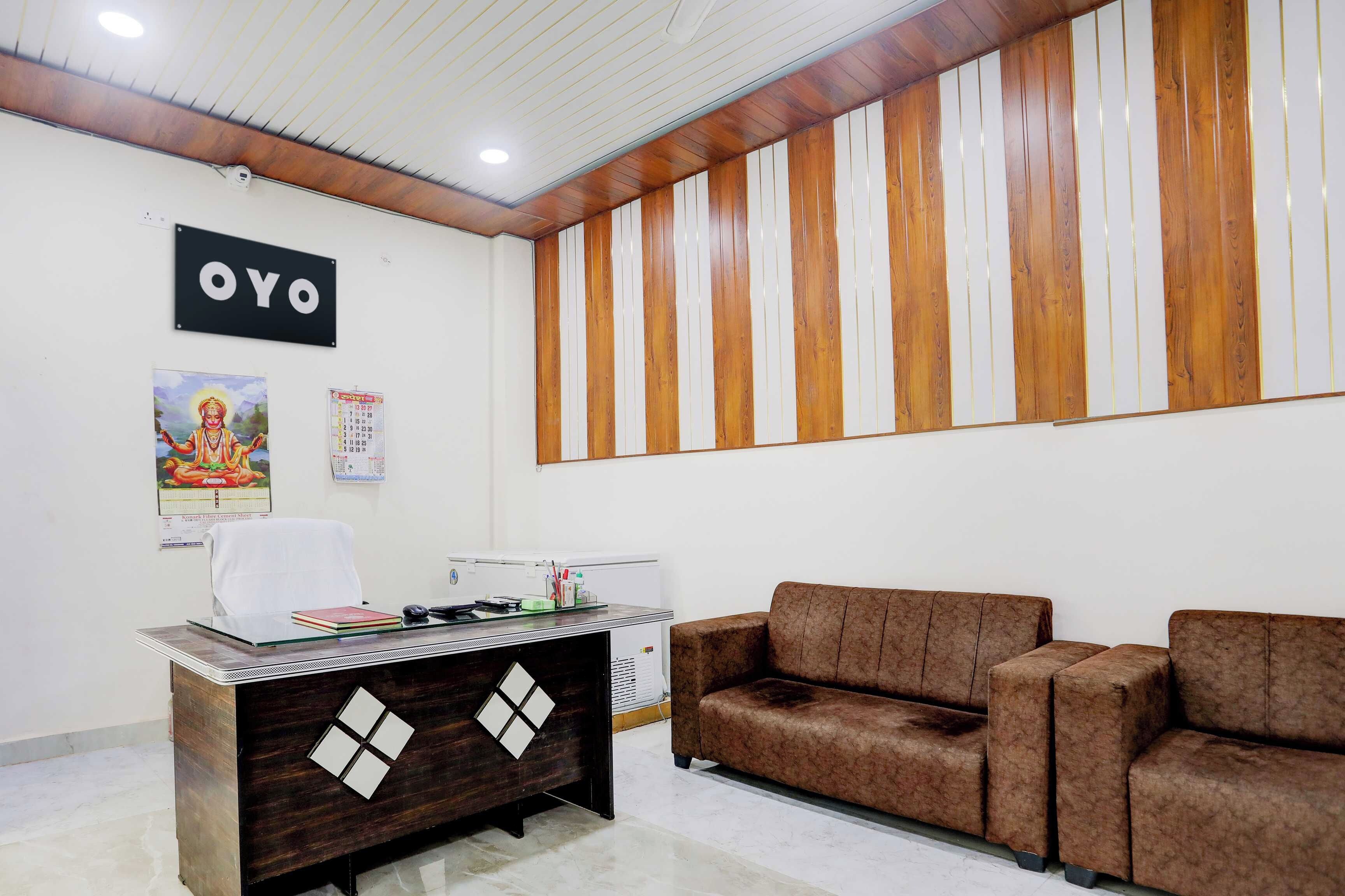 Un espace d’accueil comprenant un comptoir, un canapé, un mur recouvert de panneaux de bois verticaux et une enseigne indiquant « OYO ».