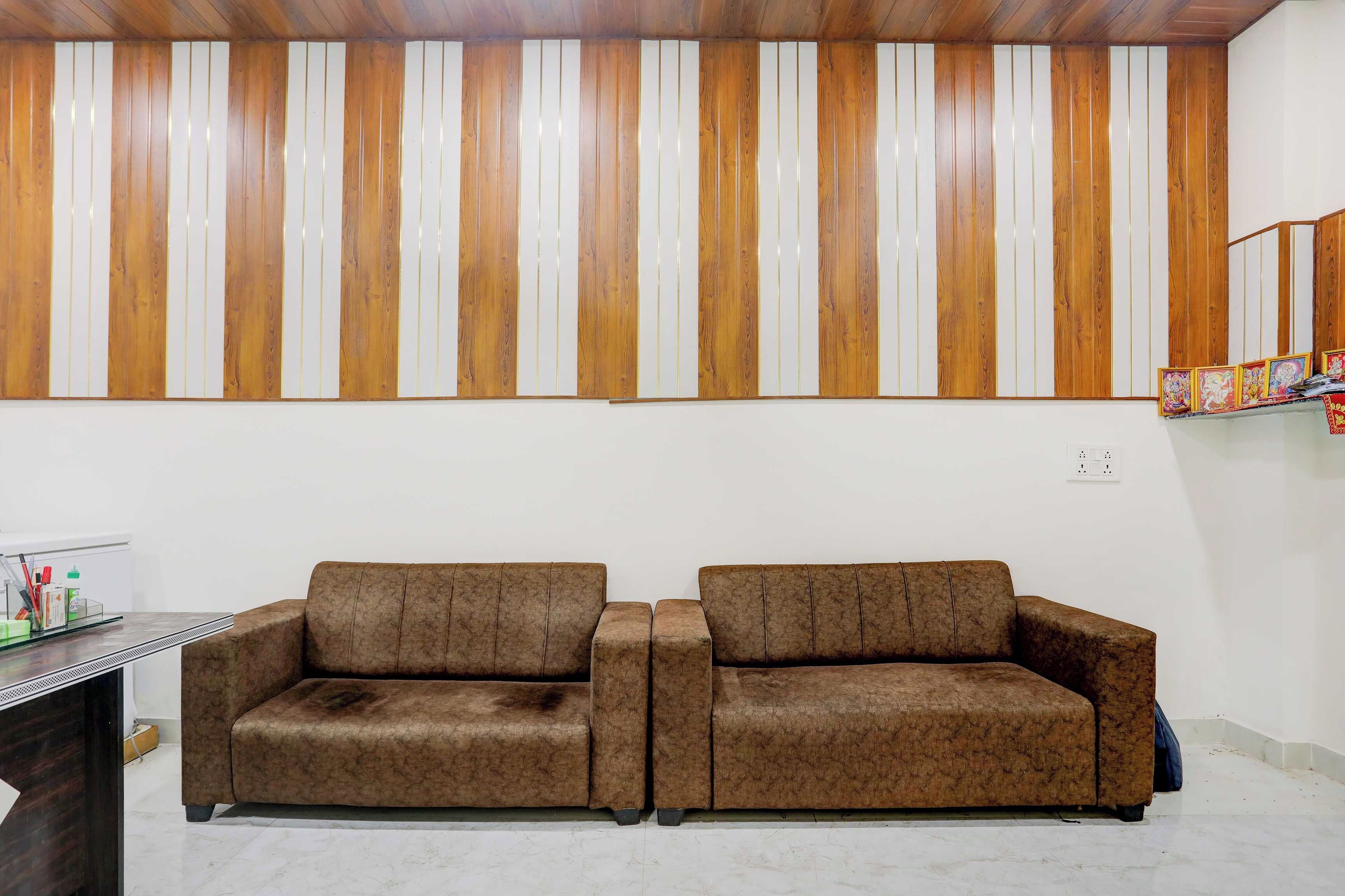 Une pièce avec deux canapés marron, un plafond en bois et un mur blanc orné de panneaux de bois verticaux.