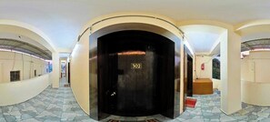 A corridor with a black elevator marked with the number 302, leading to a room with a red carpet. - Hotel O Moonland (Brahmapur)