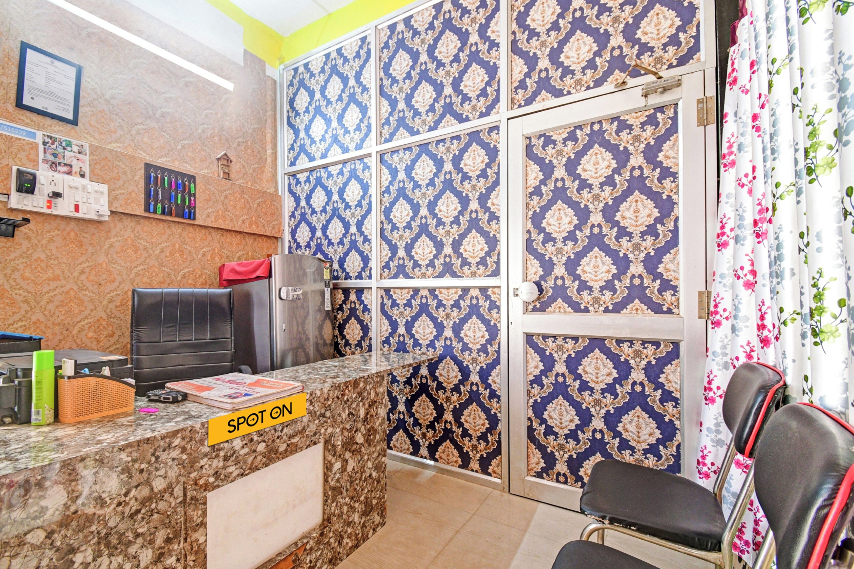 A reception desk with a 'SPOT ON' sign, a seating area with a chair, and patterned wallpaper.