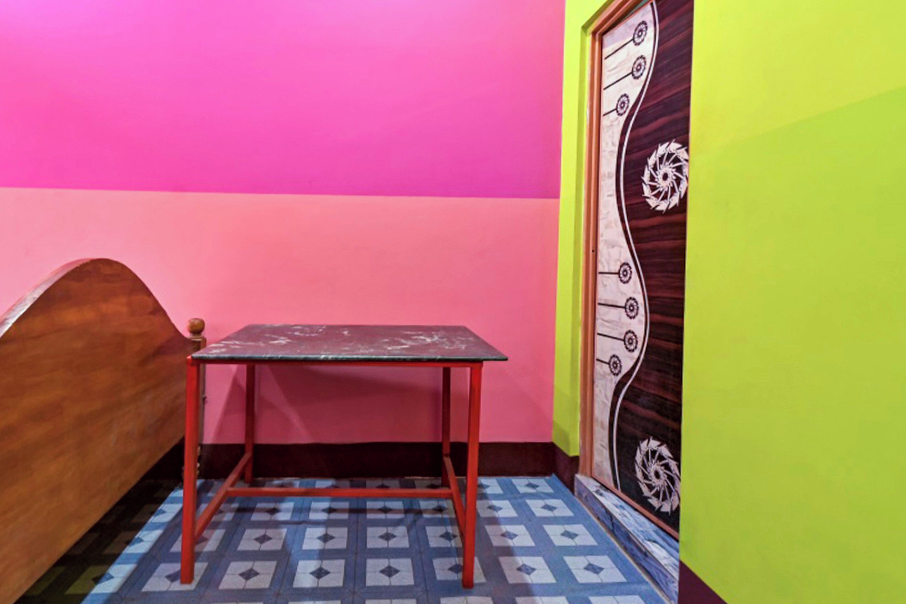 A room with a bed, a small table, and a door with a decorative design.
