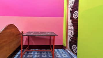 A room with a bed, a small table, and a door with a decorative design.