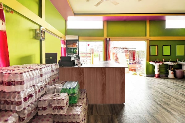A reception area with a wooden counter, a refrigerator, and a stack of bottled water. - Hotel O WELCOME RESORT & FAMILY (Sarupeta)