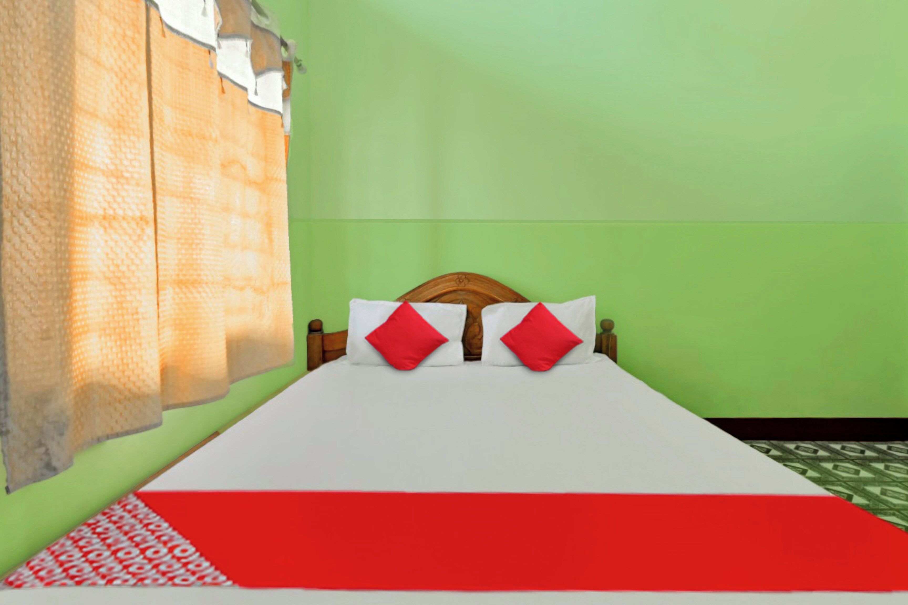 Una cama con colcha blanca y roja, cabecera de madera y almohadas rojas.