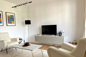 A modern living room with a flat-screen TV, white furniture, and abstract art on the wall. - Top location • Family-friendly • Parking • Netflix (Ludwigshafen am Rhein)