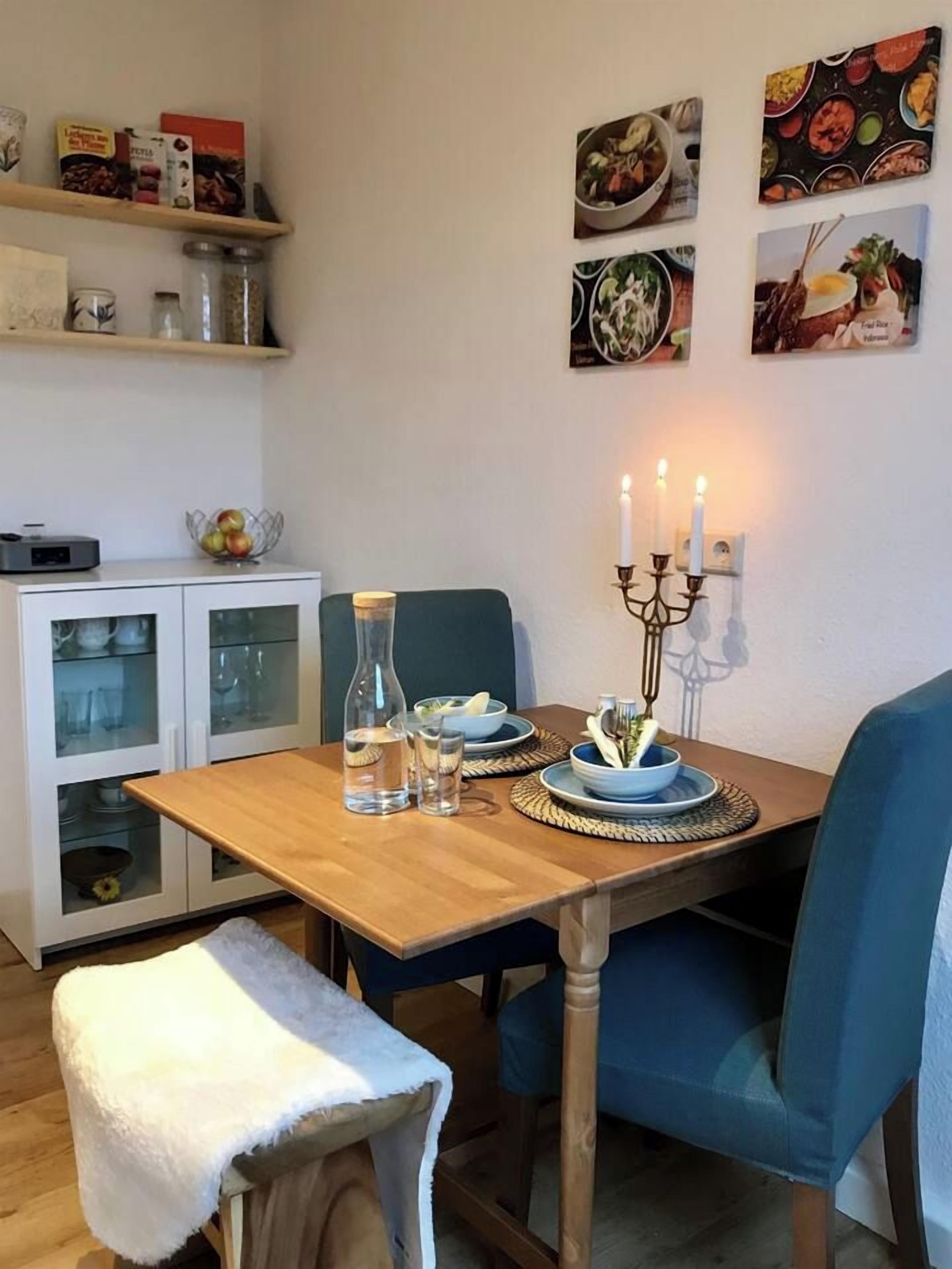 A dining area with a wooden table, blue chairs, a candle holder, and a cabinet with glass doors.