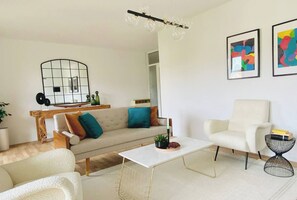 Ein Wohnzimmer mit einer Couch, Sesseln, einem Couchtisch und einer modernen Lampe.