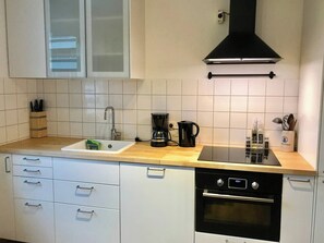 A kitchen with white cabinets, a black stove, a coffee maker, and a sink. - Top location • Family-friendly • Parking • Netflix (Ludwigshafen am Rhein)