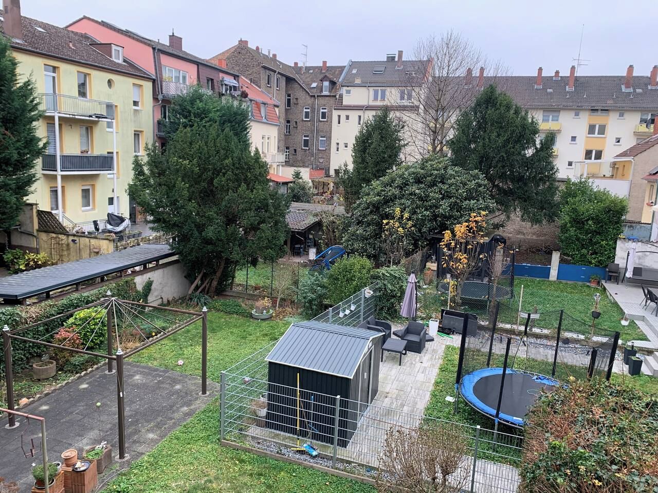 Un quartier résidentiel doté d’un jardin clôturé, d’un trampoline et d’un petit abri de jardin.