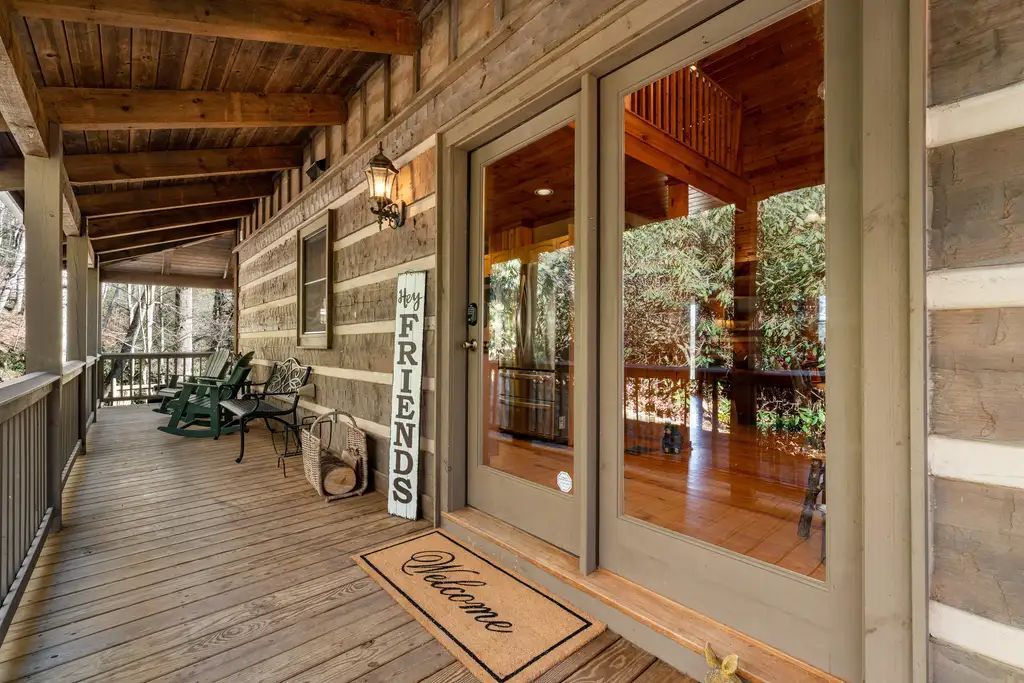 Covered wooden porch with outdoor seating leading to a glass entrance door.
