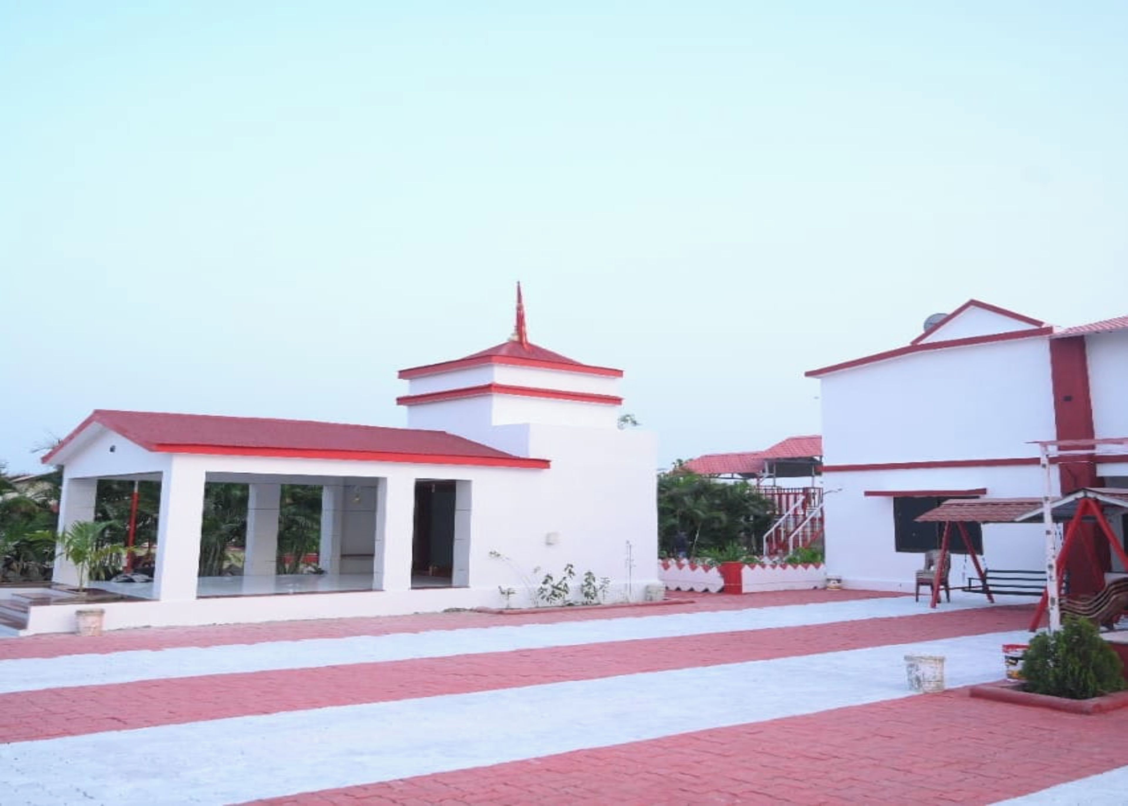 A building with a central tower, a covered area with columns, and a separate structure with a red roof.