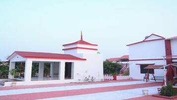 A building with a central tower, a covered area with columns, and a separate structure with a red roof.