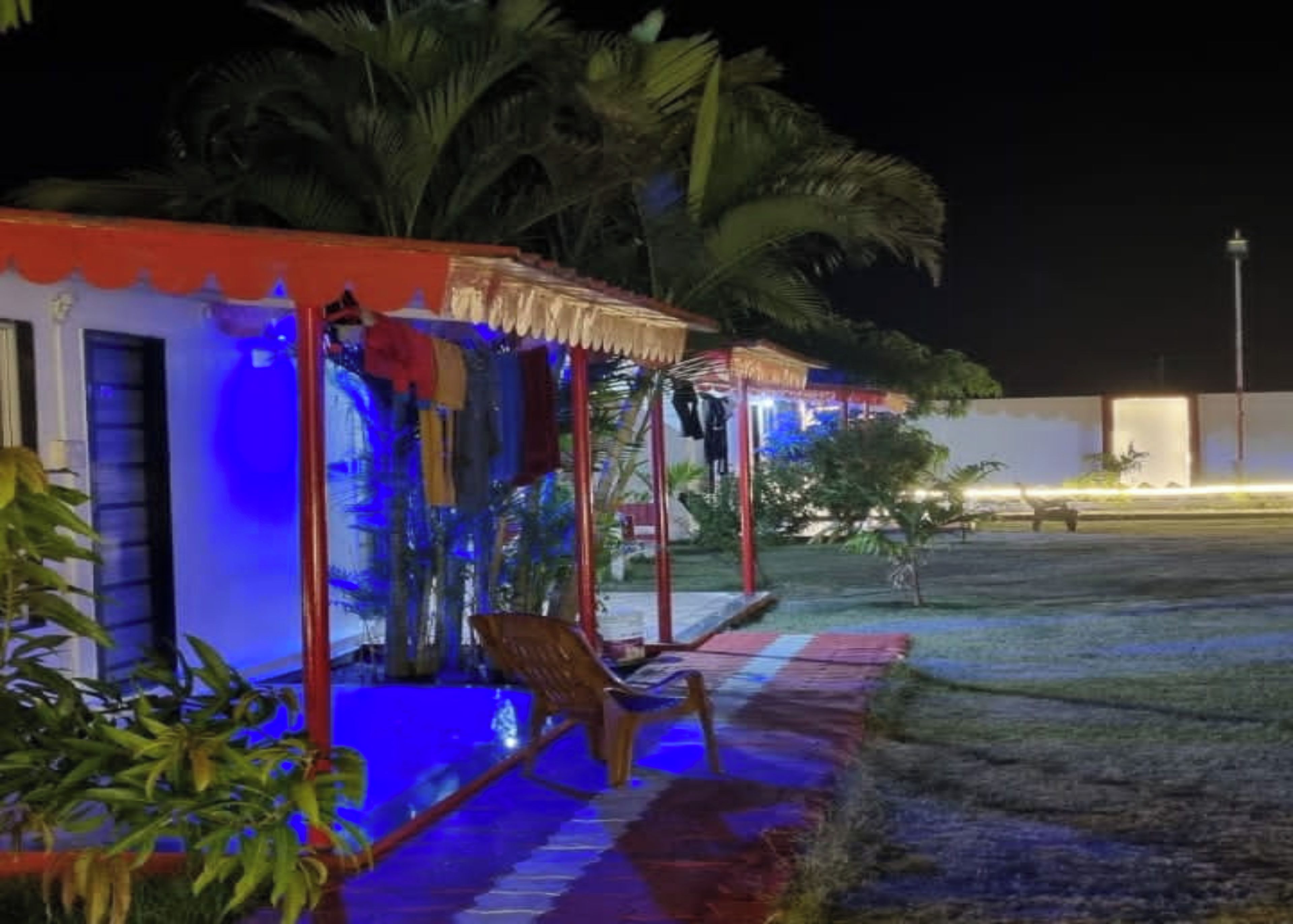 Ein Gebäude mit überdachter Außenbereich, einem Pool und Palmen.