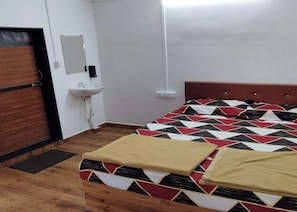 Une pièce comprenant un lit, une table de chevet, une lampe fixée au mur et une porte.