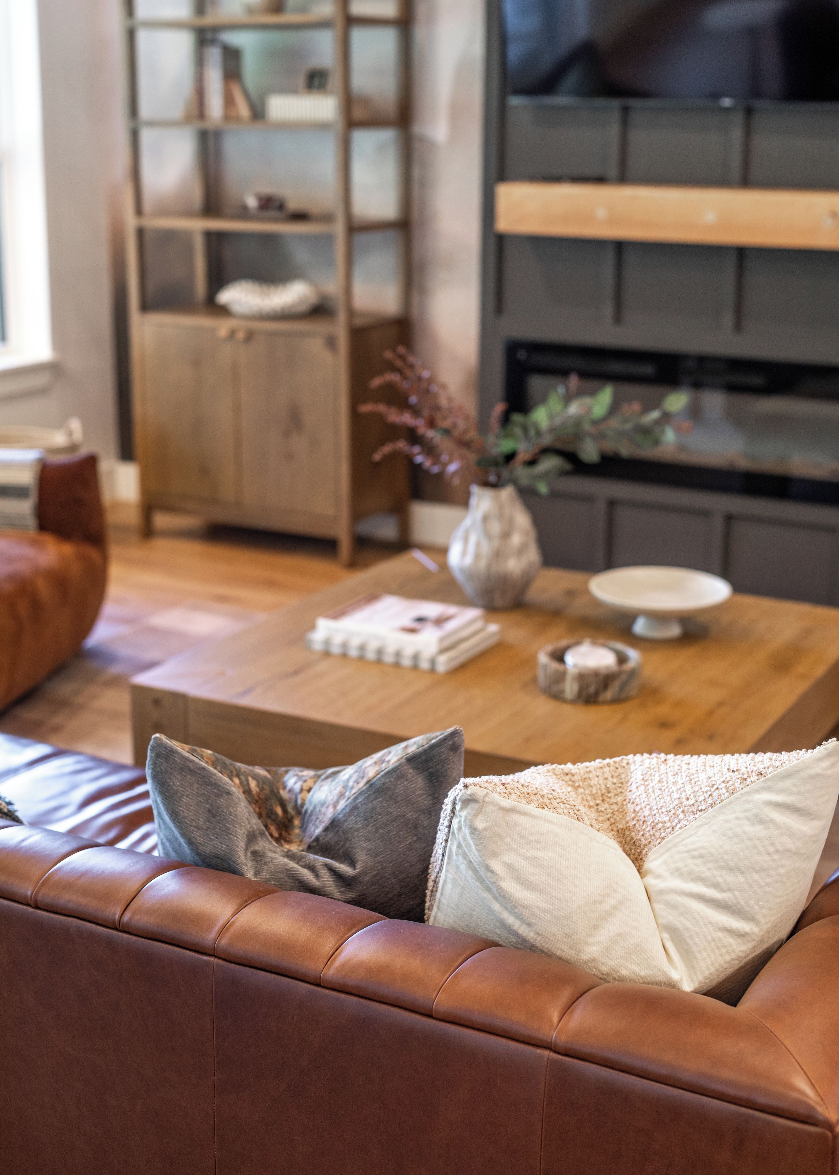 A living room with a leather sofa, a wooden coffee table, and a bookshelf.
