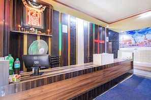 A reception desk with a computer, a water bottle, and a glass with a drink. - Hotel O Sri Sai Samrat Lodge (Bangalore)