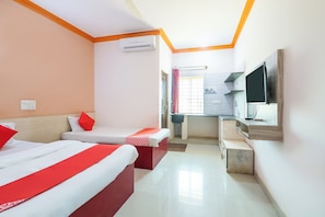 A hotel room with two beds, an air conditioning unit, a television, and a small kitchenette. - Hotel O Sri Sai Samrat Lodge (Bangalore)