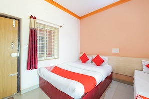 A hotel room with a bed, a window with curtains, a wall socket, and a door. - Hotel O Sri Sai Samrat Lodge (Bangalore)
