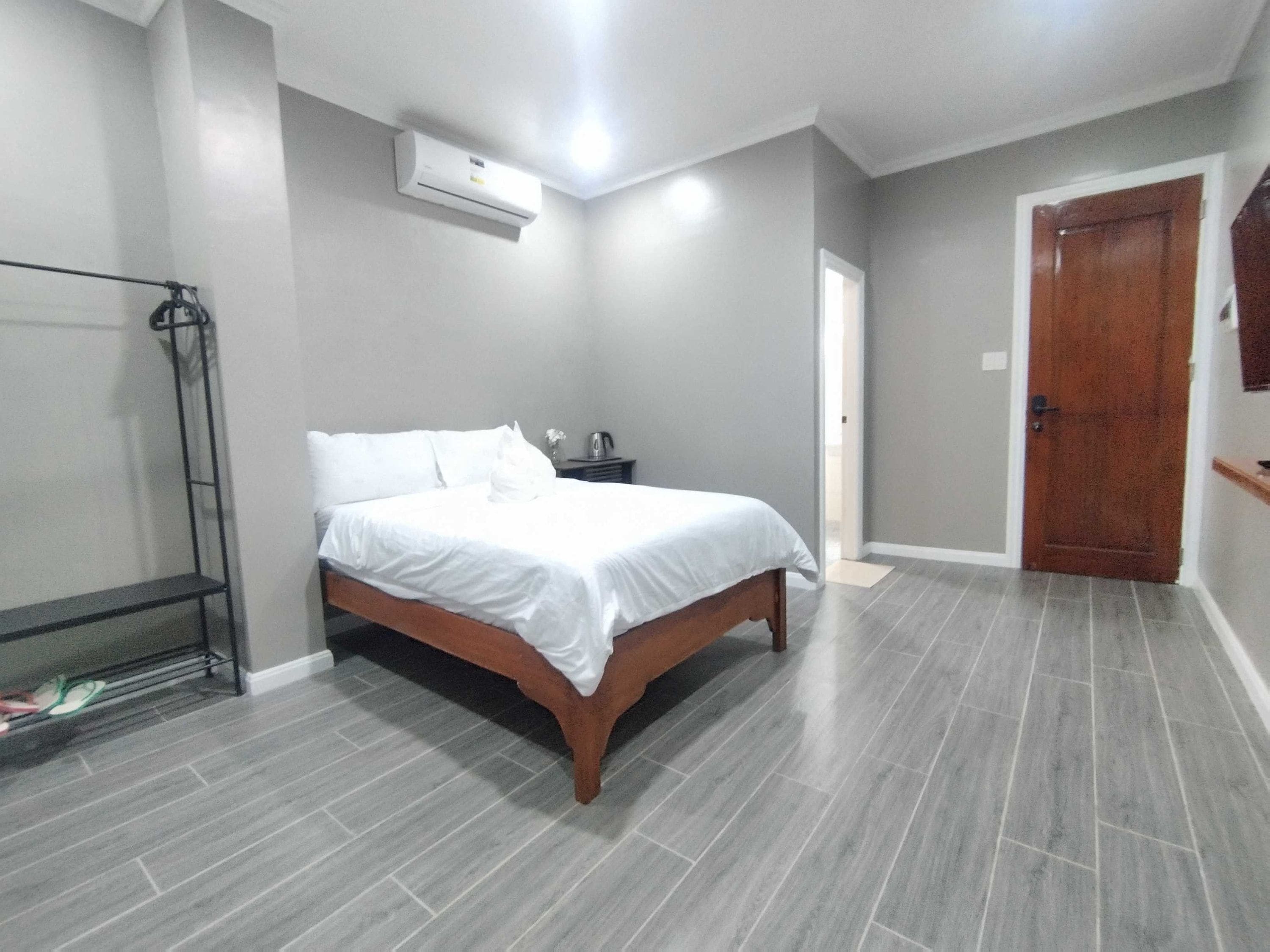 Una camera da letto con un letto, un comodino, un condizionatore d'aria a parete e una porta.