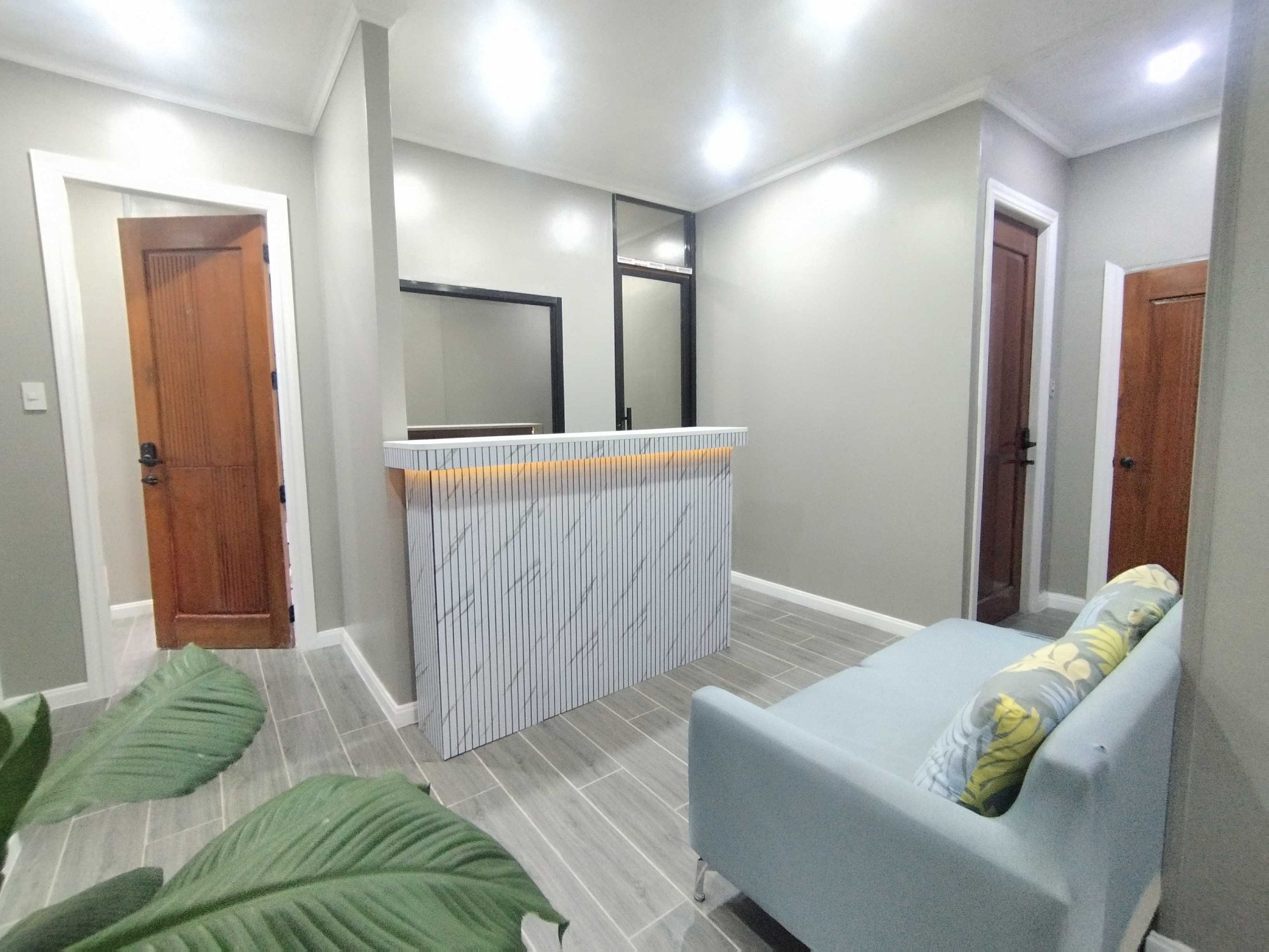 A room with a grey sofa, a small table, and a mirror on the wall.