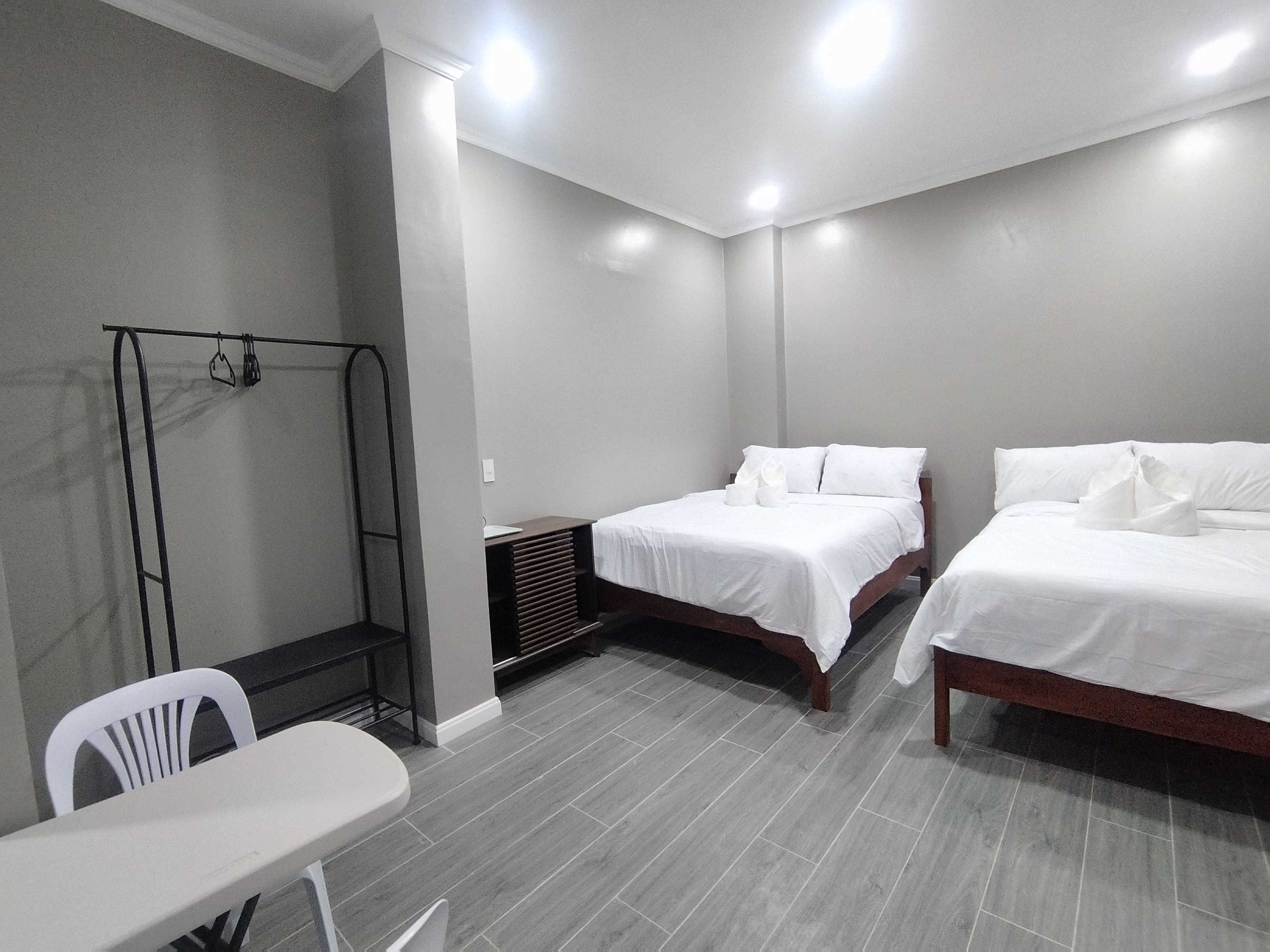 A hotel room with two beds, a small table, and a chair.