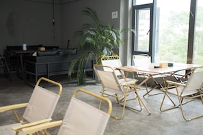 Una habitación con una mesa, sillas, una planta en maceta y una ventana con vistas.