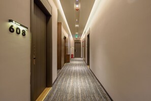 Pasillo de hotel con puertas numeradas 608 y 601, piso alfombrado e iluminación empotrada.