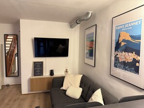 A modern living room with a flat-screen TV, a framed poster of Saint Jeannet, and a wooden bench. - New Listing (Vence)