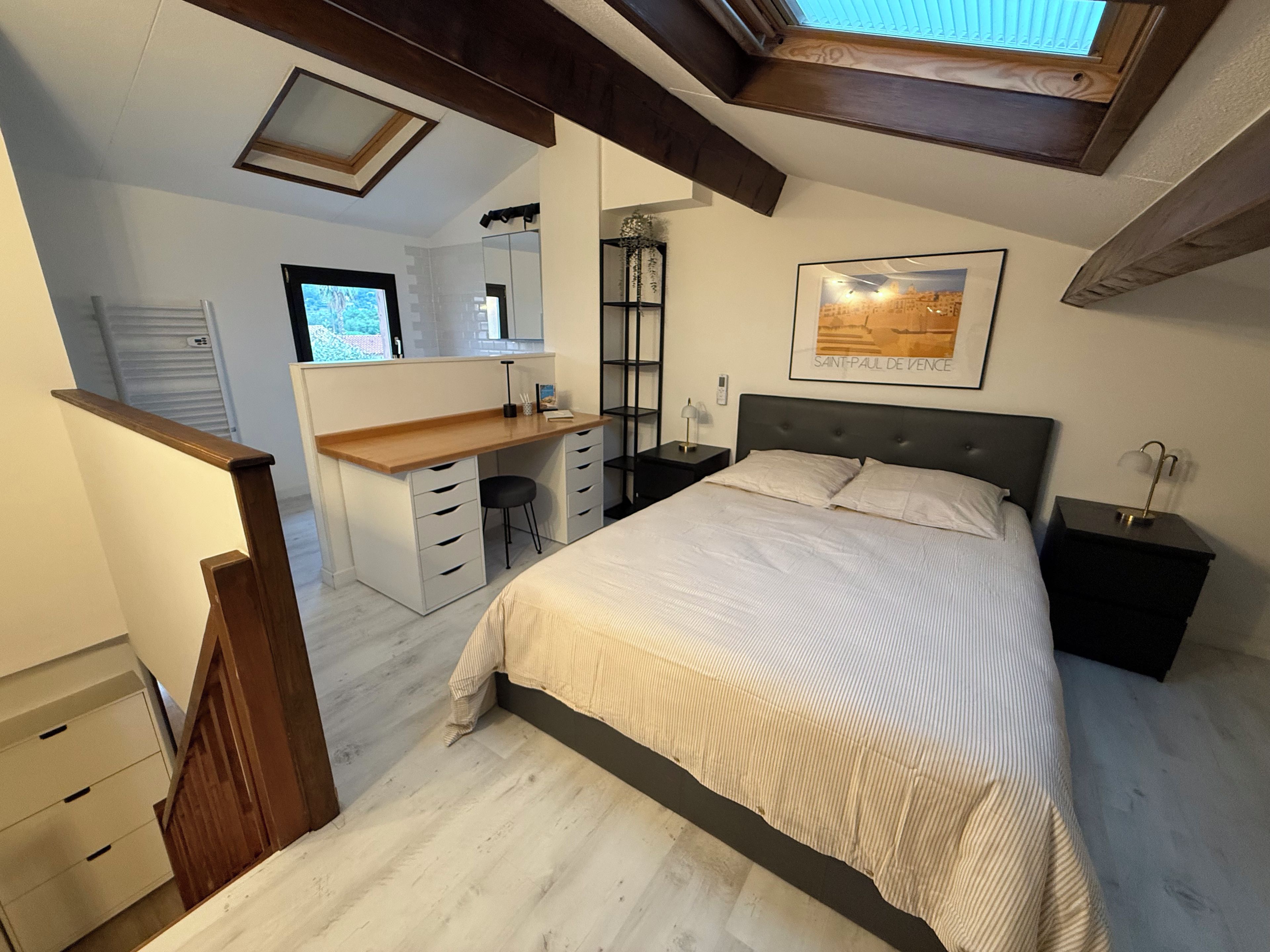 A bedroom with a bed, a desk, a chair, a nightstand, and a window.