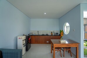 Una cocina compacta con comedor, refrigerador, microondas y pileta.