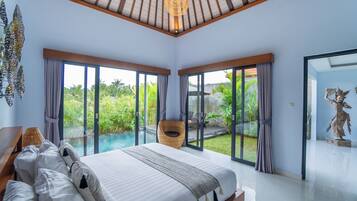 A bedroom with a large bed, a view of a swimming pool, and a statue.