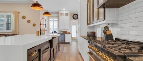 A modern kitchen with a central island, stainless steel appliances, and pendant lighting.