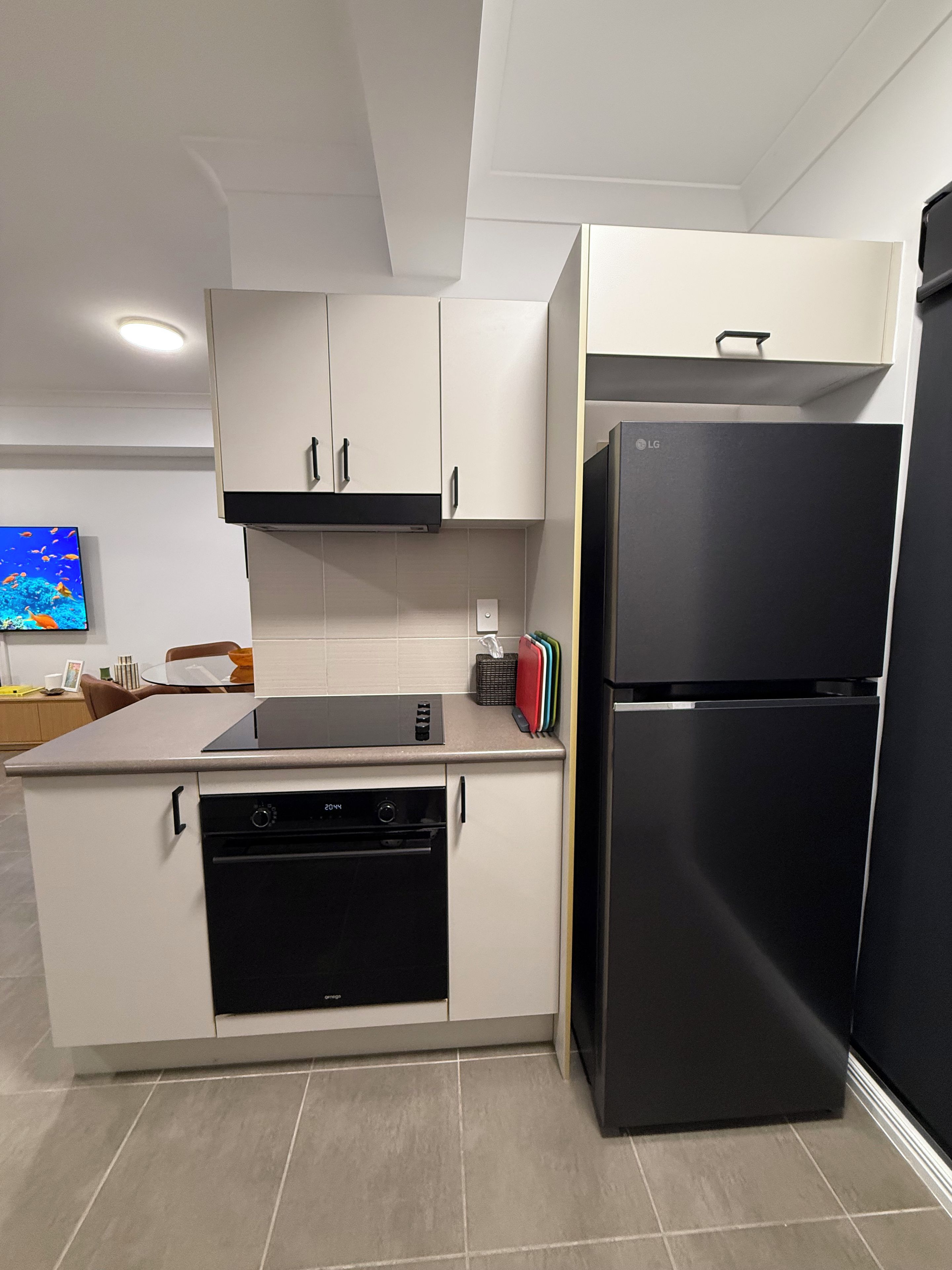 A modern kitchen with white cabinets, a black refrigerator, and a built-in dishwasher.