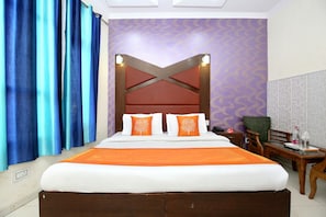 Una camera d'albergo con un letto grande, due cuscini, un comodino, una sedia e una parete con motivo decorativo.