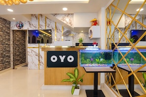A reception area with a marble wall, a reception desk labeled 'OYO', and two aquariums. - Hotel O Royal Imperial (Chapra)